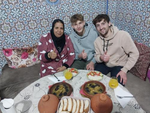 un gruppo di tre persone seduti intorno a un tavolo con cibo di Riad Elkorchi a Fes