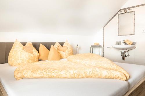 a bed with gold and white pillows and a sink at Biobauernhof Tonimörtl in Mariapfarr