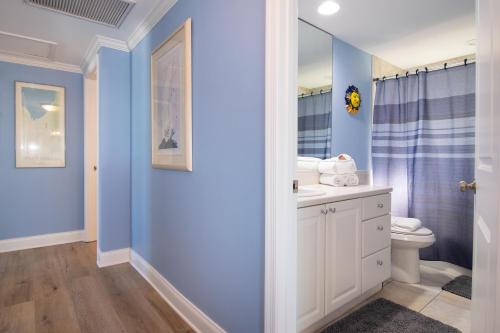baño con paredes azules, aseo y lavamanos en The Tiki House, en Holmes Beach