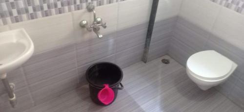 a bathroom with a toilet and a black trash can at Hotel Rajendra in Chinchani