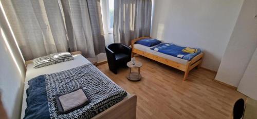 um pequeno quarto com 2 camas e uma cadeira em Rooms & Apartments Schwäbisch Gmünd em Schwäbisch Gmünd