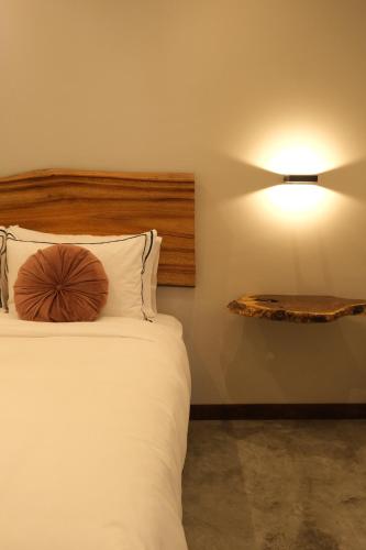 1 cama con cabecero de madera y una luz en la pared en UKO Urban Ekolodge, en Armenia