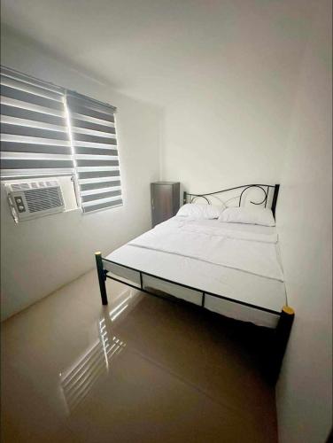 een bed in een witte kamer met een raam bij Bachelorette Rental in Ormoc