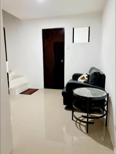 a living room with a black chair and a table at Bachelorette Rental in Ormoc