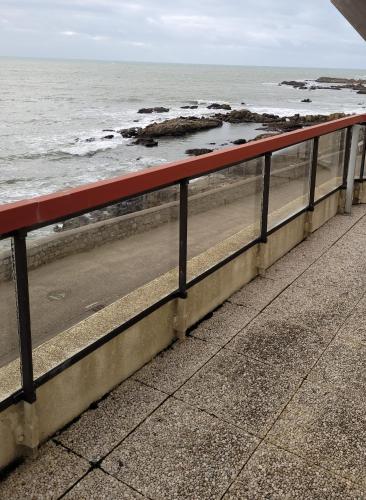 a red bench on the beach near the ocean at Panorama & Océan - Les Gîtes de la Côte d'Amour in Batz-sur-Mer