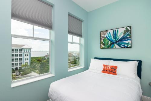 a blue bedroom with a bed and two windows at One Particular Harbour Sound View 379-401 in Bradenton