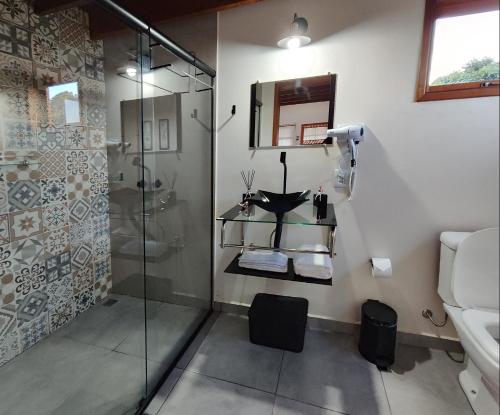 uma casa de banho com um chuveiro e uma cabina de duche em vidro. em Chalés Ninho do Poeta em Gonçalves