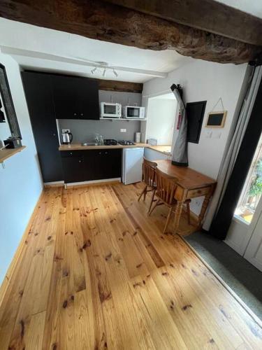 Cottage including secret garden في La Trinité-Porhoët: مطبخ مع طاولة وأرضية خشبية