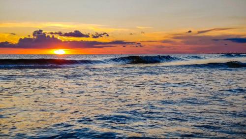 a sunset over the ocean with a wave at Bayview Inn #101 in Bradenton Beach