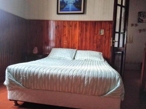 a bed in a bedroom with a wooden wall at El balcón de la Tata in San Salvador de Jujuy