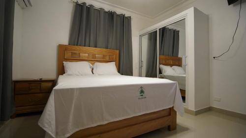 um quarto com uma grande cama branca e um espelho em Villa Sol Taino, Hotel en Boca chica, 5 minutos del Aeropuerto Internacional las Américas em La Golondrina