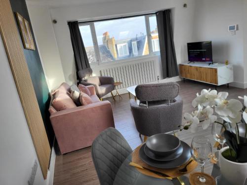 ein Wohnzimmer mit einem Sofa, Stühlen und einem Tisch in der Unterkunft 20 mins to central London, Stylish sky views 2 bed in London