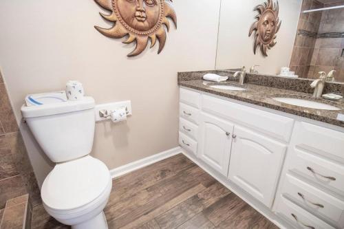 a bathroom with a toilet and a sink and a mirror at Oceanfront Escape with Private Porch 1st Floor in Pawleys Island