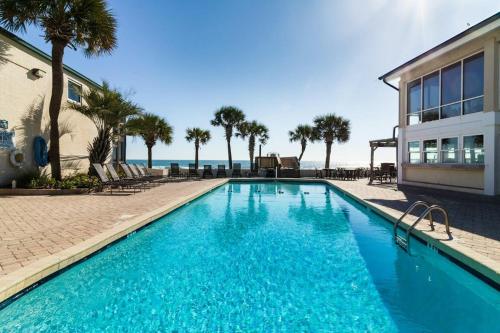a swimming pool in front of a building with palm trees at Oceanfront Escape with Private Porch 1st Floor in Pawleys Island
