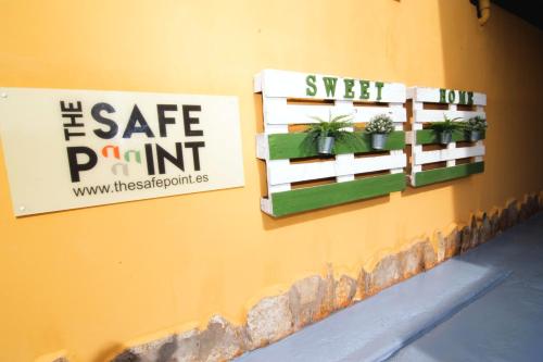 dos letreros en una pared con macetas. en The Safe Point Residential Castillo, en Castillo del Romeral