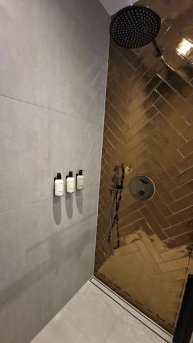 ein Bad mit Dusche und 3 Flaschen an der Wand in der Unterkunft Het Huis Met De Groene Deur in Amsterdam