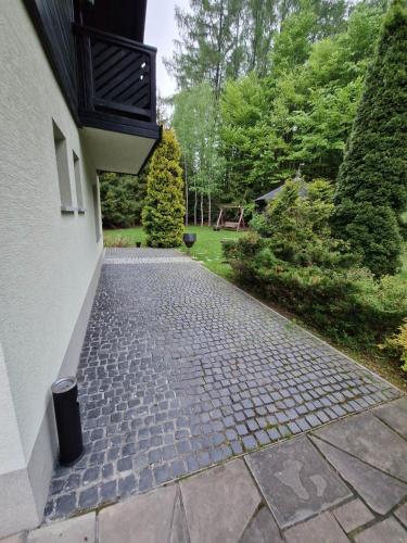 a brick walkway next to a building with trees at Villa Falsztyn Holiday Home in Falsztyn