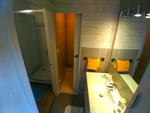 a bathroom with a sink and a shower with yellow towels at Le Chaubier in Eyliac