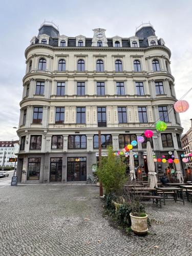 un grand bâtiment avec des tables et des parasols devant lui dans l'établissement LE Vacation 3-Room-City-Apartment, Küche, Neflix, Free TV, à Leipzig