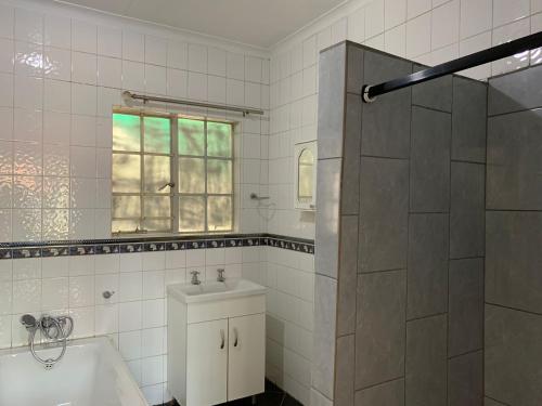 La salle de bains est pourvue d'une baignoire, d'un lavabo et d'une douche. dans l'établissement TnB Guesthouse, à Middelburg