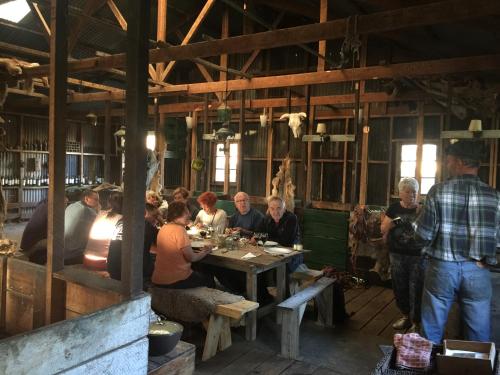 a group of people sitting at a table in a barn at Estancia Santa Thelma in Gobernador Gregores