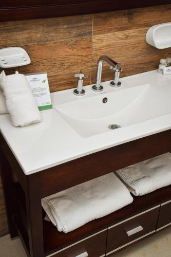 a bathroom counter with a white sink and towels at Howard Johnson Plaza & Convention Center Spa La Plata in La Plata