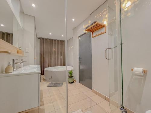 un bagno con vasca, lavandino e doccia di Amoris Guesthouse - Sandton a Johannesburg