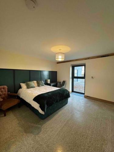 a bedroom with a large bed and a chair at Moig Lodge - 8 Double Bedroom Barn Conversion in Limerick