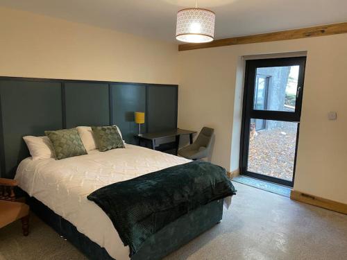 a bedroom with a large bed and a window at Moig Lodge - 8 Double Bedroom Barn Conversion in Limerick