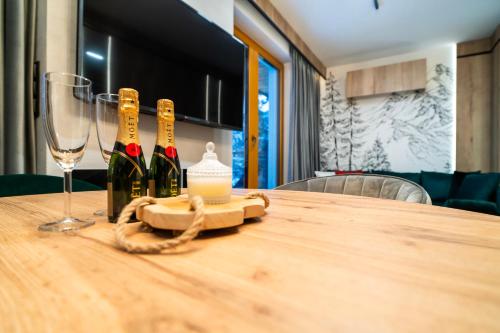 a table with three bottles of wine and a glass at Apartament pod Górskim Niebem by Apart Concept Podhale in Kościelisko