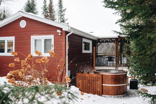 a red house with a hot tub in the snow at Cabines Niksen in Saint Adolphe D'Howard