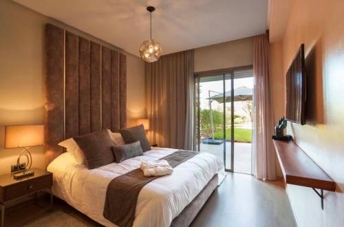 a bedroom with a large bed and a sliding glass door at Appartement de luxe avec jardin privé in Marrakesh