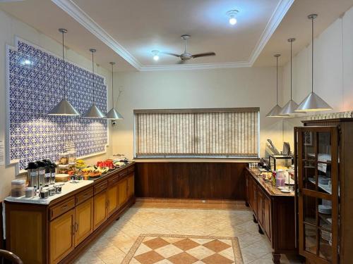 a large kitchen with wooden cabinets and a window at Hotel Casa Grande Orlândia SP in Orlândia