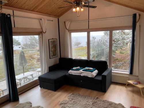 ein Wohnzimmer mit einem schwarzen Sofa vor den Fenstern in der Unterkunft Cozy Cabin in Stockholms Archipelago in Ingmarsö
