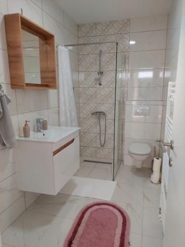 uma casa de banho com um chuveiro, um lavatório e um WC. em Apartmani Halilčević em Dubrave Gornje