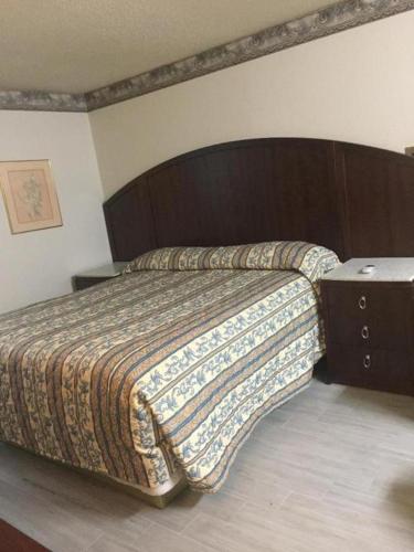 - une chambre avec un grand lit et une tête de lit en bois dans l'établissement Regency Inn Norco, à Norco