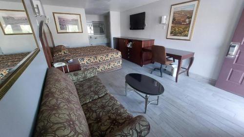 Cette chambre comprend deux lits, une table et un bureau. dans l'établissement Regency Inn Norco, à Norco