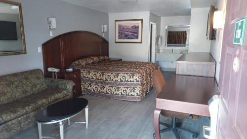 une chambre d'hôtel avec un lit et un canapé dans l'établissement Regency Inn Norco, à Norco