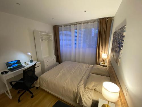 Schlafzimmer mit einem Bett, einem Schreibtisch und einem Fenster in der Unterkunft Charmant appartement à La Défense - Très proche de Paris - A côté des transports in Courbevoie