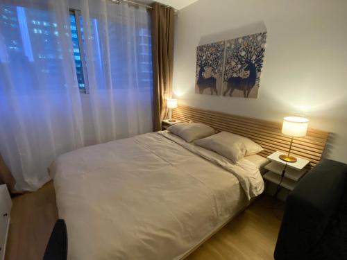 ein Schlafzimmer mit einem weißen Bett und einem Fenster in der Unterkunft Charmant appartement à La Défense - Très proche de Paris - A côté des transports in Courbevoie