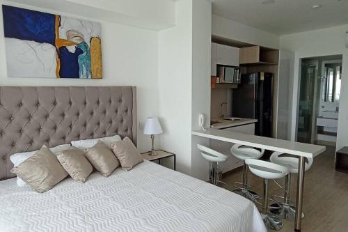 1 dormitorio con 1 cama blanca, mesa y sillas en New Beach loft in Cartagena close to the airport, en Cartagena de Indias