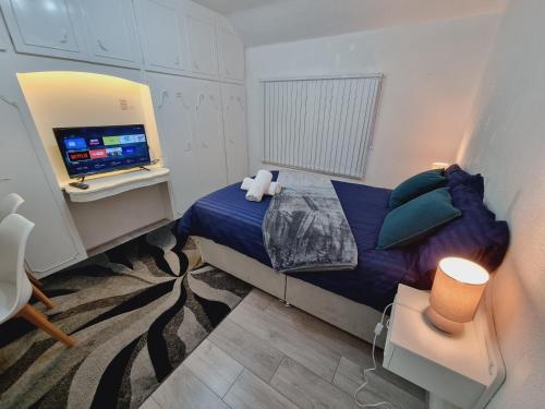 um pequeno quarto com uma cama e uma televisão em Modern 3 bedroom house, 3 Bathroom, secure parking, Wi-Fi & Garden em Leeds