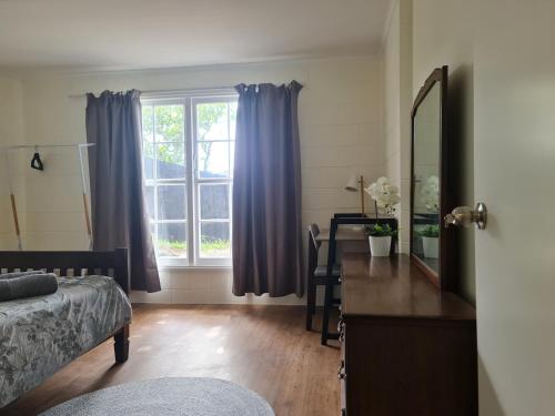 a bedroom with a bed and a dresser and a window at Hillcrest Villa in Auckland