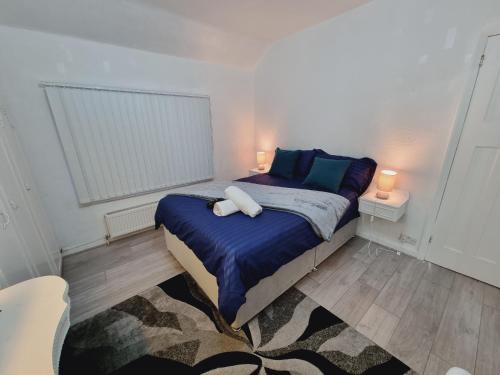 a small bedroom with a bed with a blue comforter at Modern 3 bedroom house, 3 Bathroom, secure parking, Wi-Fi & Garden in Leeds