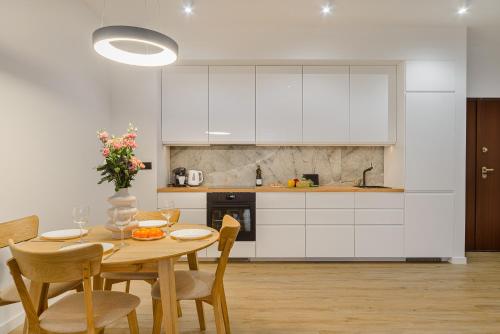 a kitchen with white cabinets and a table and chairs at P&O Apartments Sułkowicka - Mokotów in Warsaw