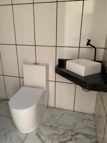 La salle de bains est pourvue de toilettes blanches et d'un lavabo. dans l'établissement Pousada São Benedito, à Cachoeira Paulista