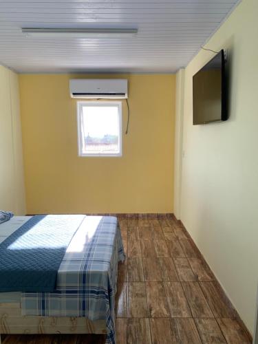 a bedroom with a bed and a window and a television at Pousada São Benedito in Cachoeira Paulista