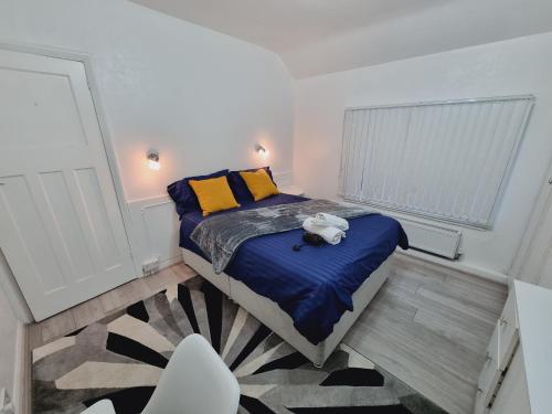 een slaapkamer met een bed met blauwe lakens en gele kussens bij Modern 3 bedroom house, 3 Bathroom, secure parking, Wi-Fi & Garden in Leeds