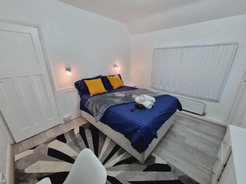 a bedroom with a bed with blue sheets and yellow pillows at Modern 3 bedroom house, 3 Bathroom, secure parking, Wi-Fi & Garden in Leeds