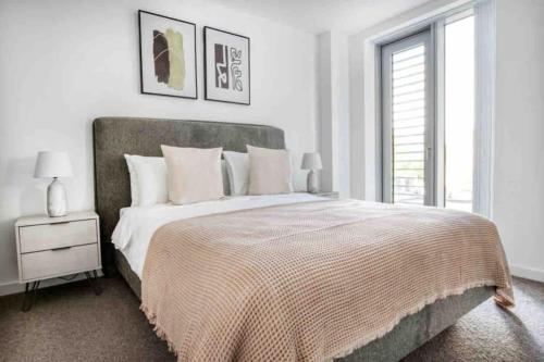 a white bedroom with a large bed and a window at Brand New 1 Bed Modern Apartment in London